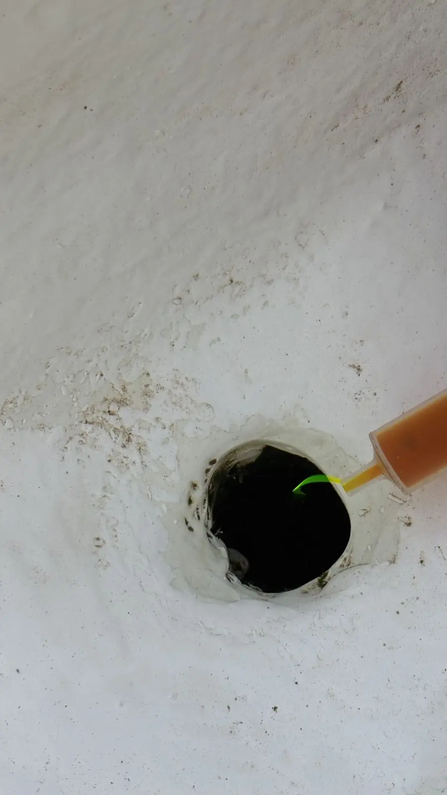 Aplicación de tinte con jeringa en un orificio del vaso de una piscina