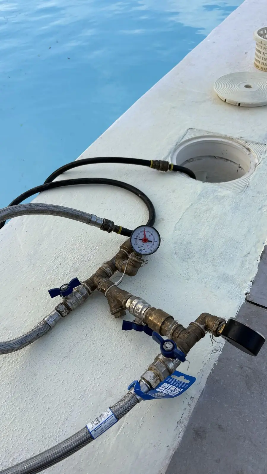 Colector con manómetro conectado a las tuberías de una piscina desde el borde del vaso