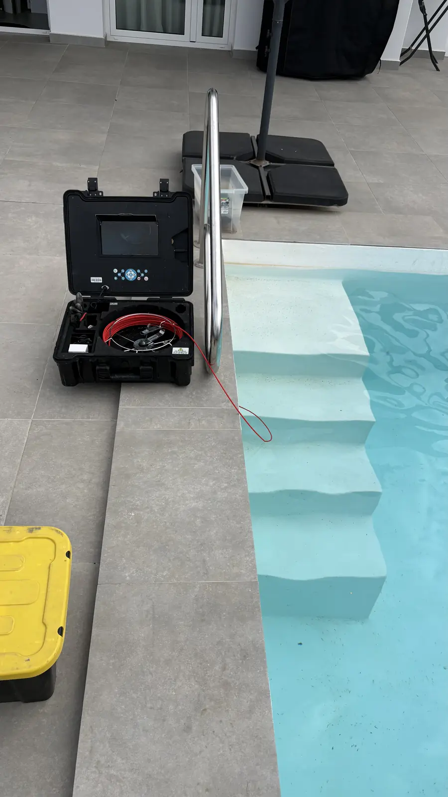 Maletín de cámara de inspección abierto junto al borde de una piscina