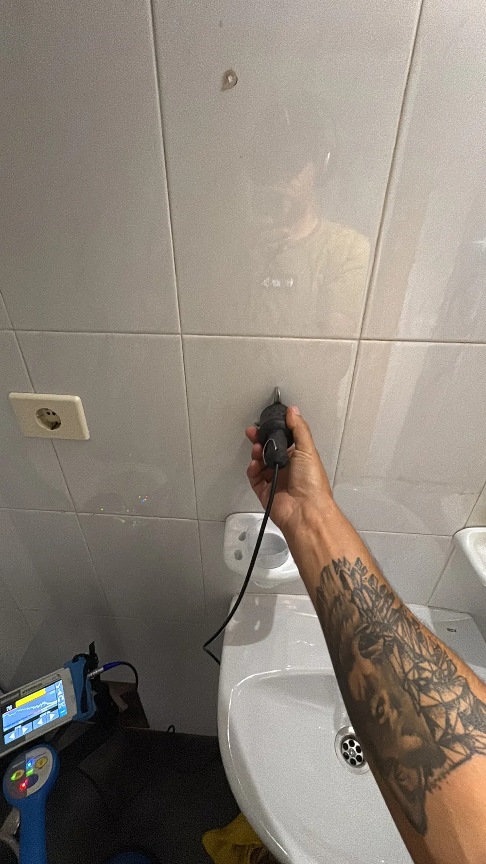 Micrófono de contacto apoyado sobre la pared alicatada de un baño, con el sebaKMT HYDROLUX midiendo el ruido de la fuga a 400 Hz