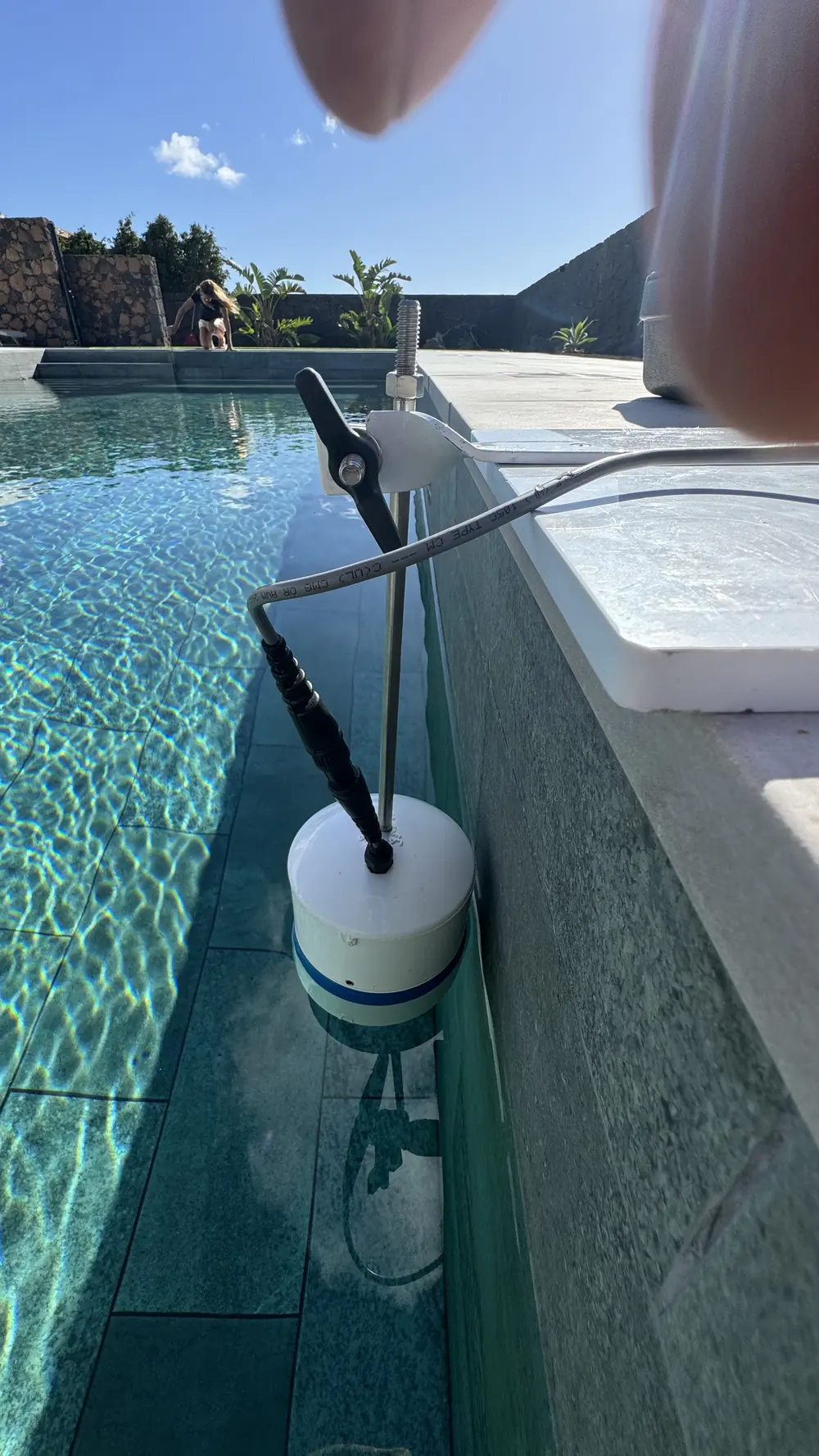 Sensor flotante del LeakTrac colocado en el agua junto al borde de una piscina durante el barrido electrónico del vaso